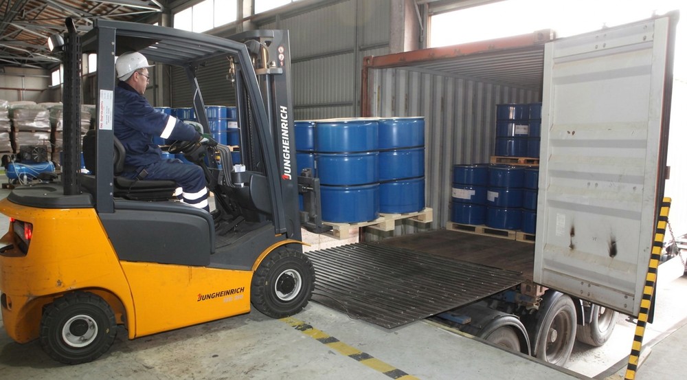 Forklift loading barrels into a shipping container